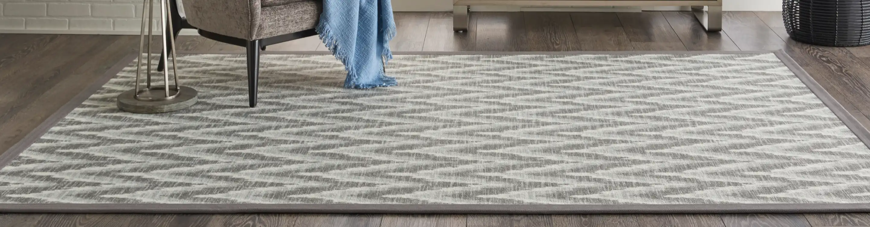 Beige and grey zig-zag area rug with chair. 